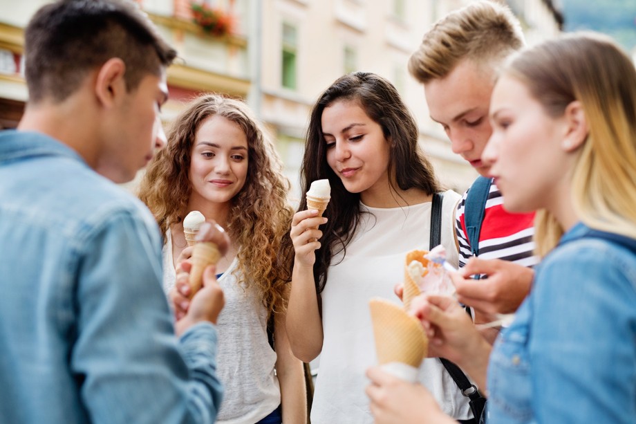 Attractive teenage students in town eating ice cream.